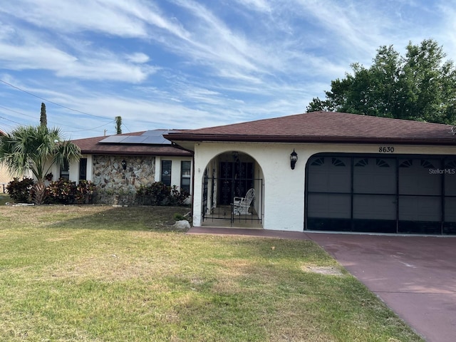 8630 Winter Haven Dr, Hudson, FL 34667 - ranch-style house featuring stucco siding, a front yard, roof mounted solar panels, a garage, and driveway