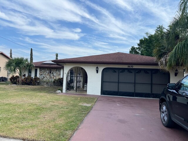 8630 Winter Haven Dr, Hudson, FL 34667 - view of front facade featuring an attached garage, concrete driveway, stucco siding, a front lawn, and solar panels