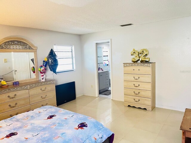 8630 Winter Haven Dr, Hudson, FL 34667 - bedroom featuring light tile patterned floors, a textured ceiling, ensuite bath, and baseboards