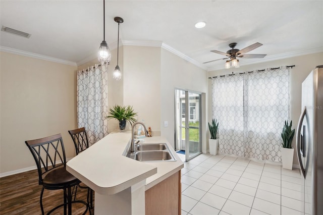 kitchen with visible vents, ornamental molding, a ceiling fan, a sink, and freestanding refrigerator