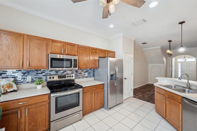 kitchen featuring a ceiling fan, a sink, appliances with stainless steel finishes, brown cabinetry, and light countertops