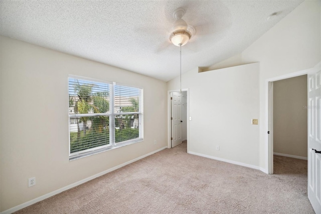 unfurnished room with baseboards, lofted ceiling, carpet flooring, a textured ceiling, and a ceiling fan