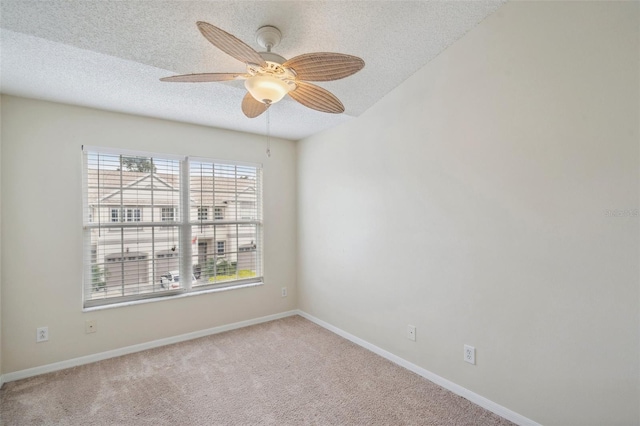 carpeted spare room featuring baseboards, a textured ceiling, and a ceiling fan