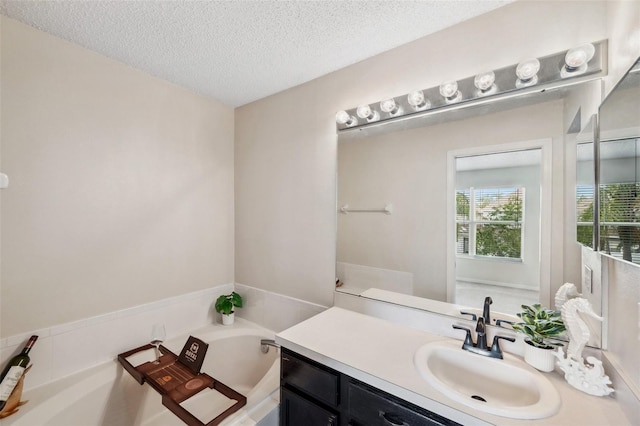 full bathroom with a garden tub, a textured ceiling, and vanity