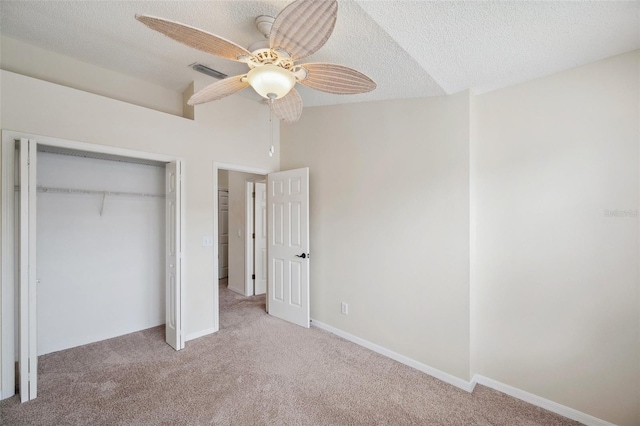 unfurnished bedroom with visible vents, a textured ceiling, a closet, carpet, and vaulted ceiling