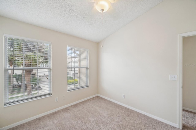 carpeted empty room with a textured ceiling, lofted ceiling, and baseboards