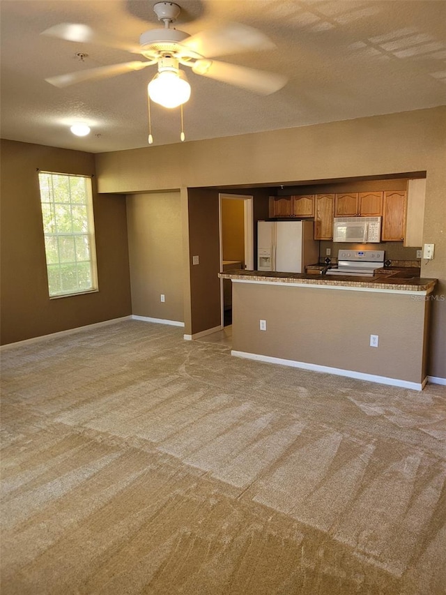 kitchen featuring white appliances, ceiling fan, kitchen peninsula, light carpet, and a textured ceiling