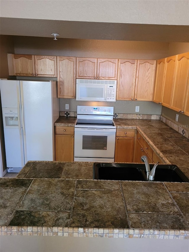 kitchen featuring sink, light brown cabinets, and white appliances