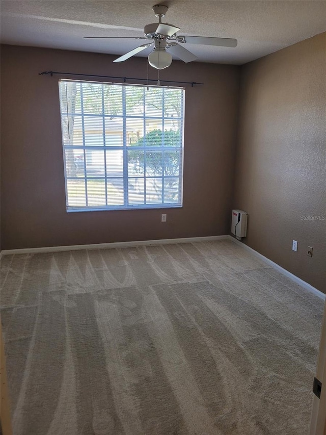 empty room with ceiling fan, a textured ceiling, and carpet flooring