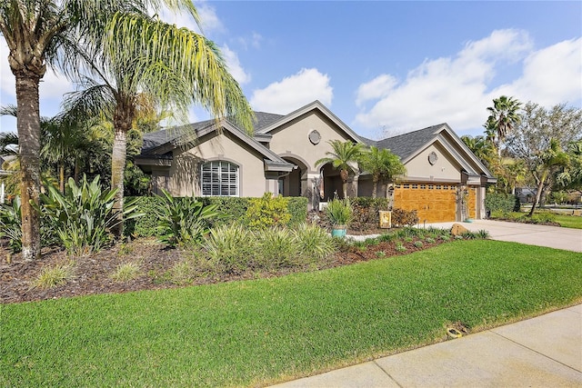 view of front of home featuring a garage, concrete driveway, a front lawn, and stucco siding