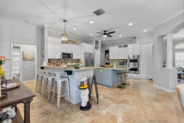 kitchen featuring visible vents, appliances with stainless steel finishes, ornate columns, a kitchen bar, and white cabinetry