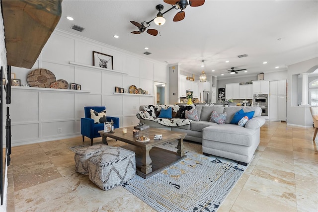 living area featuring decorative columns, visible vents, a decorative wall, ornamental molding, and ceiling fan