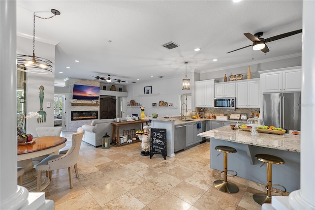 kitchen featuring a sink, visible vents, a ceiling fan, appliances with stainless steel finishes, and a glass covered fireplace