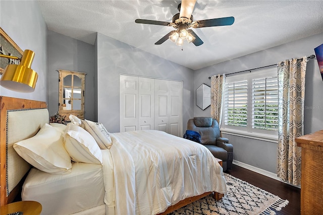 bedroom featuring a closet, a ceiling fan, vaulted ceiling, wood finished floors, and baseboards