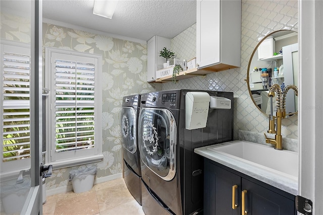 washroom with a textured ceiling, washing machine and dryer, baseboards, cabinet space, and wallpapered walls