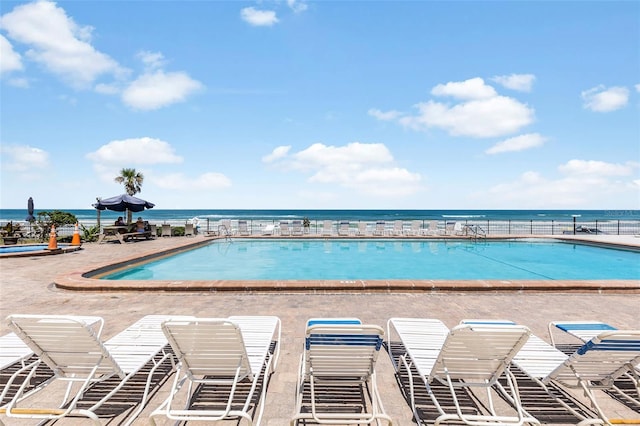 view of swimming pool featuring a water view and a patio