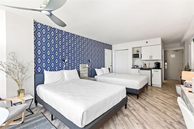 bedroom with ceiling fan, light hardwood / wood-style floors, and bar area