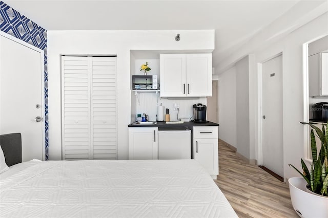 kitchen featuring light wood-type flooring, white cabinetry, sink, and dishwasher