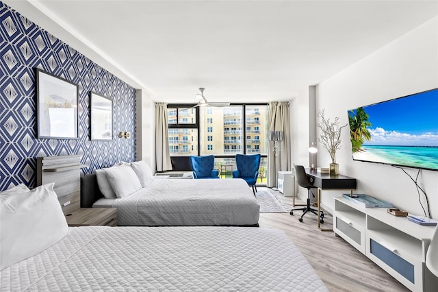 bedroom with a wall of windows and light hardwood / wood-style flooring