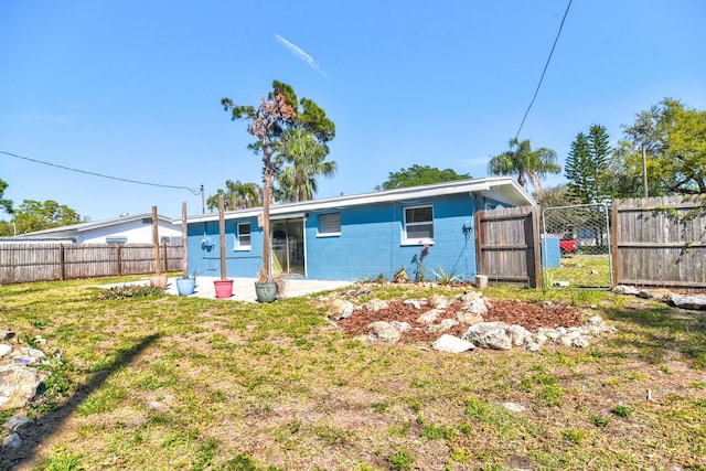 back of house featuring a gate, a fenced backyard, and a yard