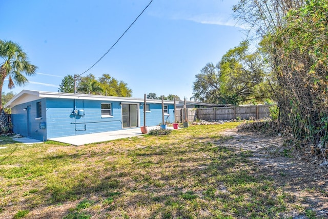 back of property featuring fence, a patio, and a lawn