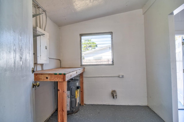 laundry area featuring concrete block wall and electric panel