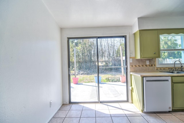 kitchen with a sink, green cabinets, light countertops, decorative backsplash, and dishwasher