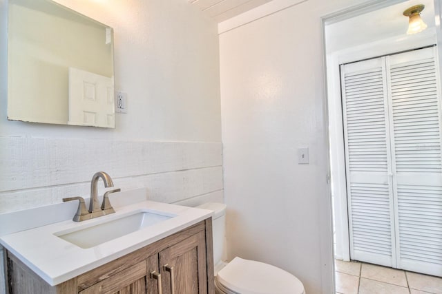 bathroom with toilet, wainscoting, tile patterned flooring, and vanity