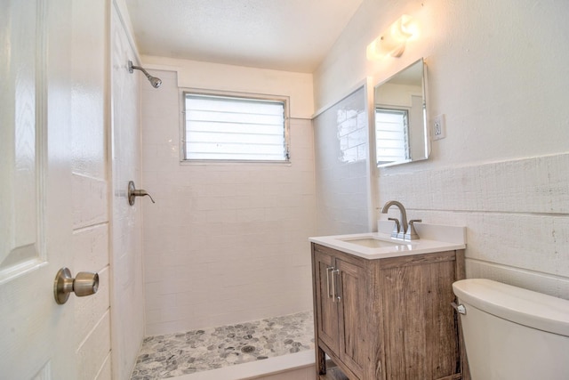 bathroom featuring toilet, a wainscoted wall, plenty of natural light, and tile walls