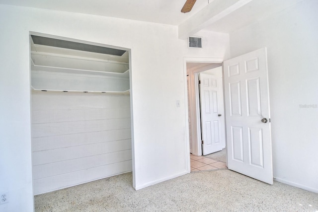 unfurnished bedroom featuring ceiling fan, speckled floor, visible vents, a closet, and beamed ceiling