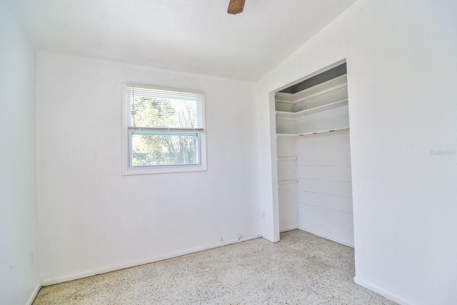 unfurnished bedroom with ceiling fan, speckled floor, and a closet