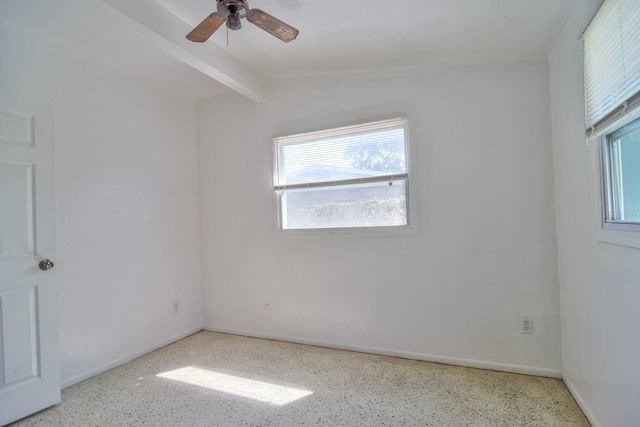 empty room with a ceiling fan, plenty of natural light, baseboards, and speckled floor