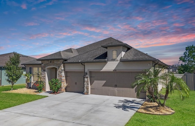 french country inspired facade featuring stone siding, a yard, an attached garage, and stucco siding