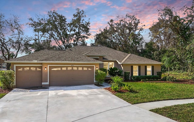 view of front of home with a front yard, driveway, an attached garage, and stucco siding