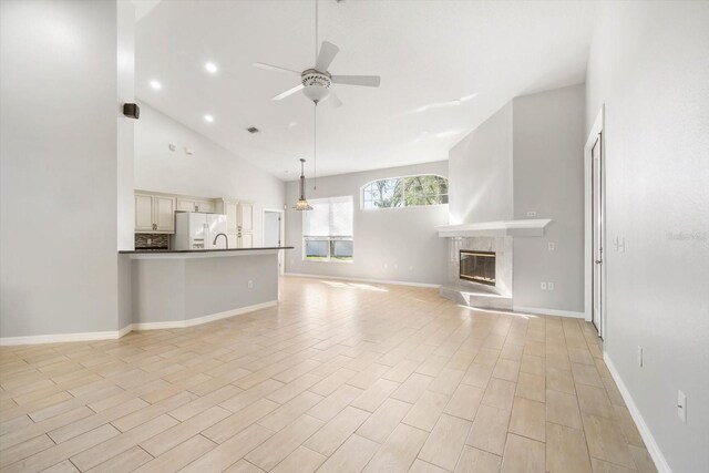 unfurnished living room with ceiling fan, light wood-type flooring, a high end fireplace, and baseboards