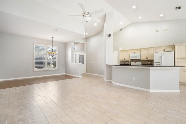 kitchen featuring dark countertops, white appliances, cream cabinets, and open floor plan