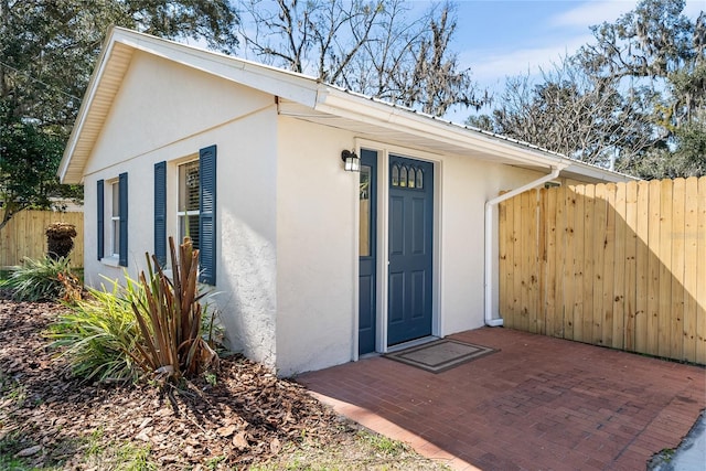 property entrance featuring fence and stucco siding