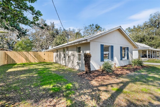 view of side of home with a yard, fence, and stucco siding