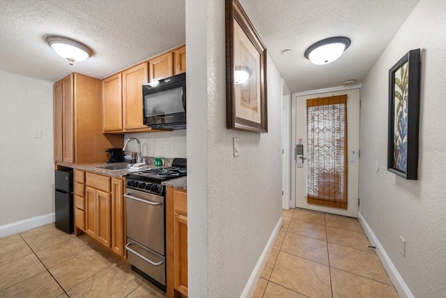 kitchen featuring light tile patterned flooring, a textured ceiling, sink, and stainless steel range with gas cooktop