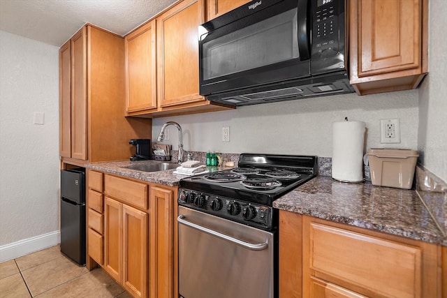 kitchen with light tile patterned floors, sink, dark stone counters, and electric range