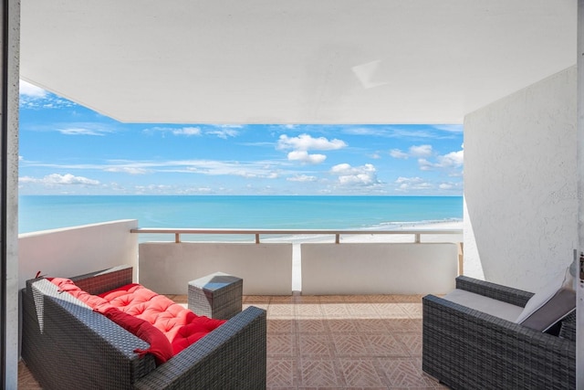 balcony with a water view and a view of the beach