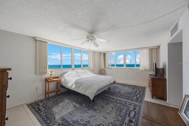 bedroom with visible vents, ceiling fan, a textured ceiling, tile patterned flooring, and baseboards