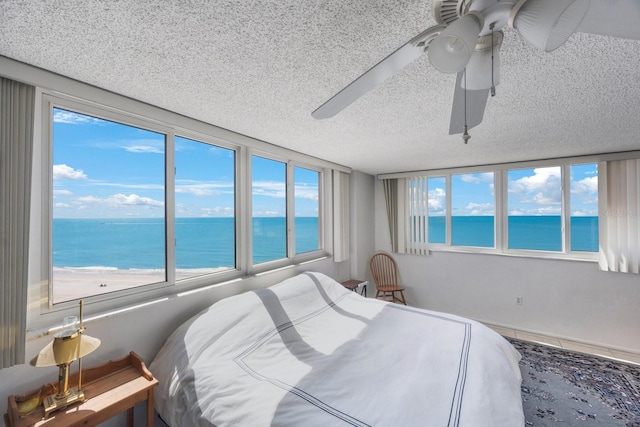 bedroom featuring a water view, multiple windows, and a textured ceiling