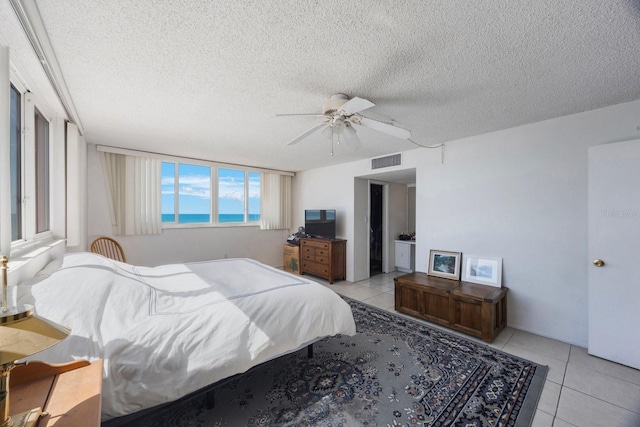 bedroom featuring a ceiling fan, visible vents, a textured ceiling, and light tile patterned flooring