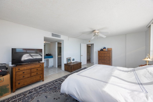 bedroom with light tile patterned floors, visible vents, connected bathroom, ceiling fan, and a textured ceiling