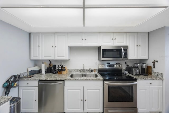 kitchen featuring backsplash, appliances with stainless steel finishes, white cabinets, and a sink