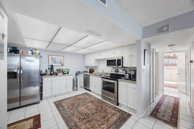 kitchen featuring a textured ceiling, stainless steel appliances, a sink, visible vents, and white cabinets