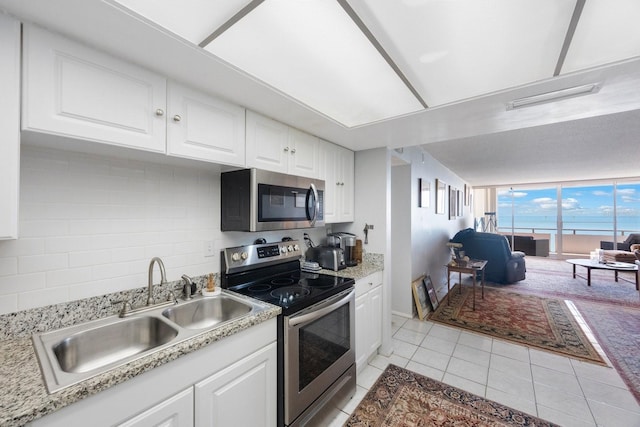 kitchen with light tile patterned floors, light countertops, backsplash, appliances with stainless steel finishes, and a sink