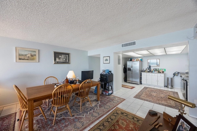 dining area featuring visible vents, a textured ceiling, and light tile patterned floors