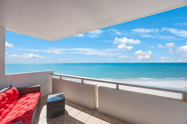 balcony featuring a view of the beach and a water view